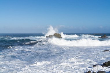 İspanya, Tenerife yakınlarındaki dalgalı Atlantik Okyanusu, sudaki kayalıklarda güçlü dalgalar kopuyor.