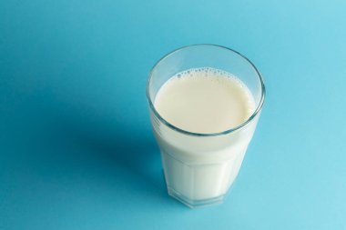 Mavi arka planda bir bardak taze süt, boşluğu kopyala
