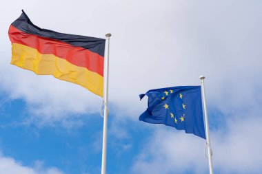 Almanya bayrağı ve mavi gökyüzünde bulutlu Avrupa bayrağı