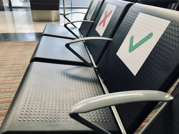 a row of empty chairs with an indication of where it is possible to sit to maintain the social safety distance during the period of the COVID-19 coronavirus pandemic. Social distancing at airport