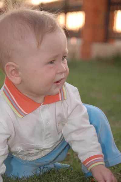 男の子が草の中に座ってかわいい赤ちゃんの小さな顔の肖像画 — ストック写真
