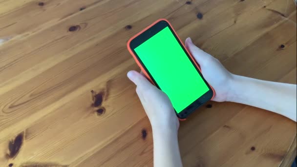 Молодий підліток використовує смартфон з зеленим екраном, який сидить на столі. Інтернет-зв'язок. Хромакі макіяж. Набивати порожні сенсорні екрани. Соціальна мережа. Інтернет - балачки. — стокове відео