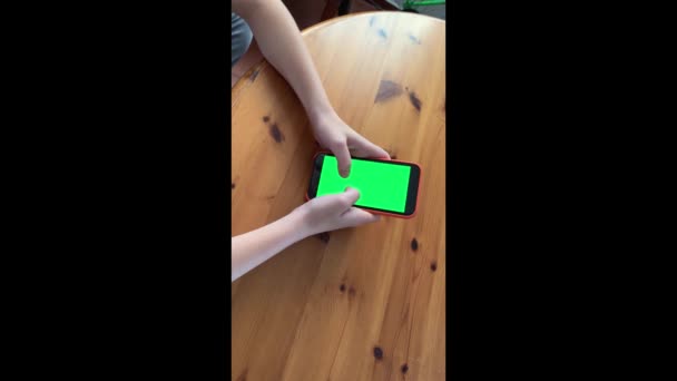 Junge Teenager-Hände mit grünem Bildschirm Smartphone auf dem Tisch sitzend. Online-Geschäftskommunikation. Chromakey-Attrappe. Tippen auf den leeren Touchscreen. Soziales Netzwerk. Internet-Chat. — Stockvideo