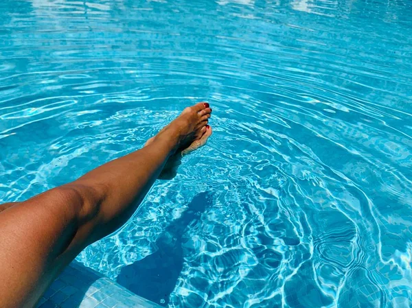 Piernas de mujer tendidas cerca de la piscina. Hermosa hembra un pie y un talón levantados hacia arriba —  Fotos de Stock