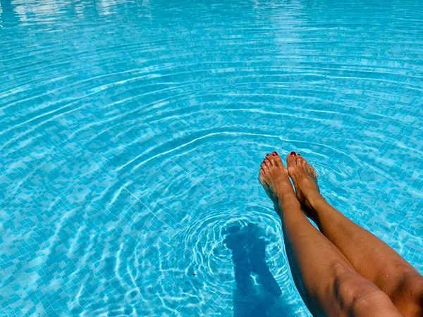 Gambe di donna sdraiato vicino alla piscina. Bella femmina un piede e un tallone sollevato verso l'alto — Foto Stock