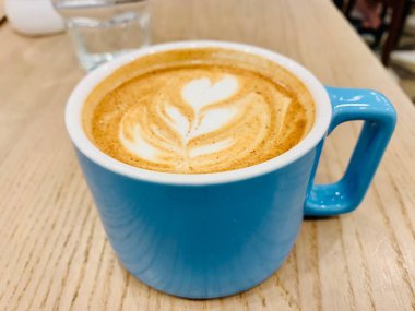 Kahverengi ahşap masada mavi kapuçino bardağı.