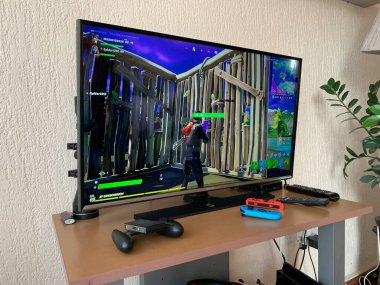 10.04.2021 Kıbrıs Rum Kesimi Paphos TV 'si, Fortnite bilgisayar oyunu ile ev karantinası sırasında kendini izole ederek ekranda yer aldı. Ekranda Oyun Bilgisayar ekranı Fortnite oyunu ile gösteriliyor, Destansı Oyunların üretimi.