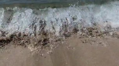 Güzel bir manzara, denizin kumlu sahilinde bir dalga akıyor, yakın plan. Yüksek kalite 4k görüntü