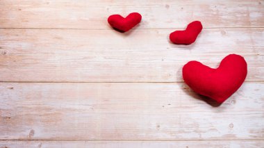 Tahta masada üç kırmızı peluş kalp. Sevgililer Günü için düz arkaplan ve harfler ya da tasarım için boş alan. Sevgililer Günü tatili için minimalist tebrik kartı..