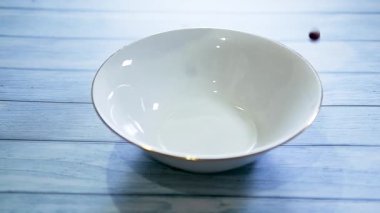 Beyaz tabak hazır kahvaltı gevreği mavi ahşap masada. Sütlü çikolatalı gevrek toplar. Fast food pişirmenin yavaş çekim videosu.