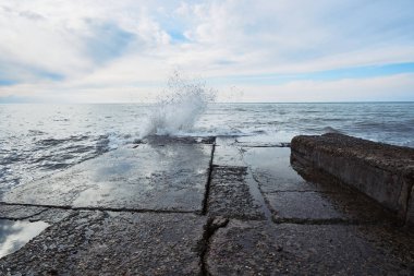 Güçlü deniz dalgaları fırtına sırasında taştan dalgalanma suyunda kırılır ve farklı yönlere sıçrar. Güzel deniz manzarası.