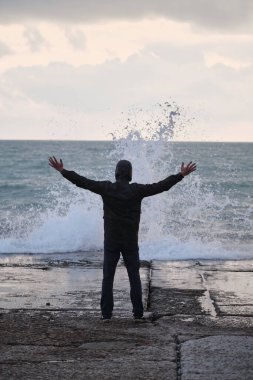 Adam beton dalgaların üzerinde duruyor ve dalgalara bakıyor. Dalgaların genç efendisi kollarını yana açmış fırtına ve fırtına çağırıyor. Okyanus doğasının inanılmaz gücü ve gücü..