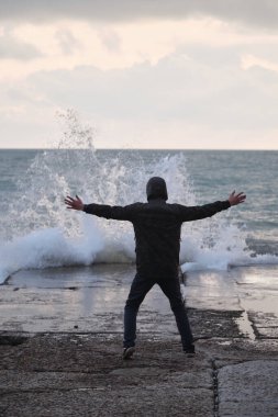 Adam beton dalgaların üzerinde duruyor ve dalgalara bakıyor. Dalgaların genç efendisi kollarını yana açmış fırtına ve fırtına çağırıyor. Okyanus doğasının inanılmaz gücü ve gücü..
