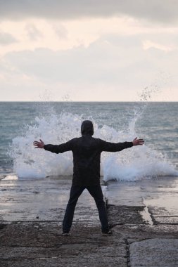 Adam beton dalgaların üzerinde duruyor ve dalgalara bakıyor. Dalgaların genç efendisi kollarını yana açmış fırtına ve fırtına çağırıyor. Okyanus doğasının inanılmaz gücü ve gücü..