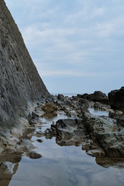 Kayalar ve mavi deniz. Okyanusa bakan büyük bir dağın yan görüntüsü. Güzel deniz manzarası.