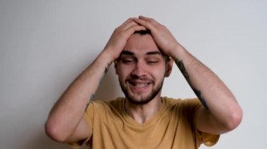 Sakallı yakışıklı Avrupalı beyaz adam hayır diye bağırdı ve iki eliyle başını tuttu. Kişi beyaz arka planda öfkenin duygularını tasvir eder..
