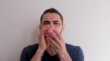 Ağzınla pembe bir balon şişir ve sonra uçup gitmesine izin ver. Sakallı, at kuyruklu, beyaz atlı, beyaz saçlı, genç, beyaz Avrupalı bir adam balonu arka planda şişiriyor..