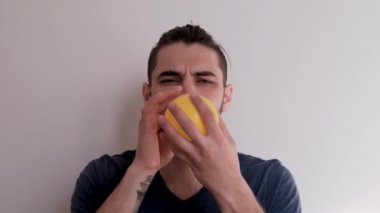 Sarı bir balonu ağızla şişir ve sonra uçup gitmesine izin ver. Sakallı, at kuyruklu, beyaz atlı, beyaz saçlı, genç, beyaz Avrupalı bir adam balonu arka planda şişiriyor..