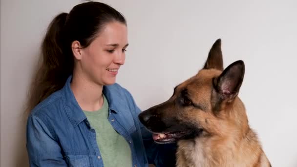 欧洲白种人的年轻漂亮姑娘亲吻她的德国牧羊犬 白种人背景的女人和狗坐在一起 彼此相爱 人与宠物之间温暖的关系 — 图库视频影像