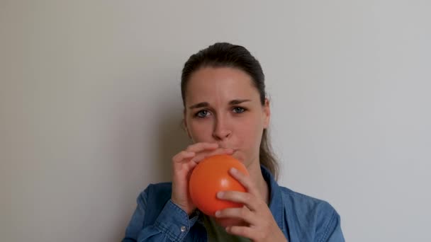 Mladá Hezká Žena Bělošského Vzhledu Nafoukne Oranžový Balón Ústy Bílém — Stock video