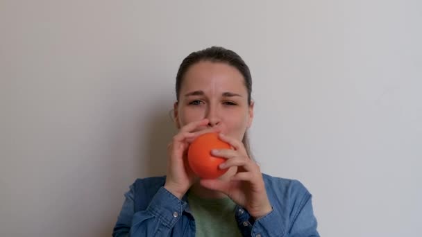 Mladá Hezká Žena Bělošského Vzhledu Nafoukne Oranžový Balón Ústy Bílém — Stock video