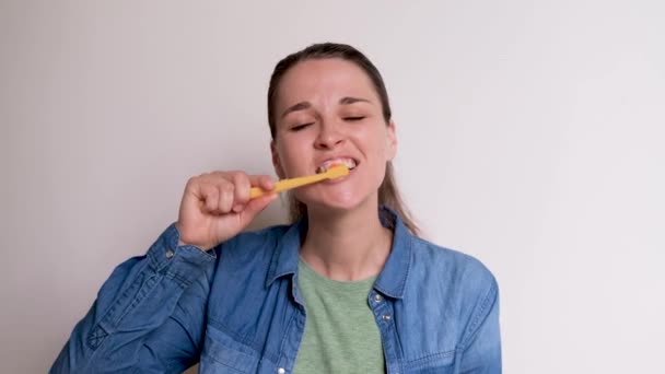 Młoda Biała Dziewczyna Niebieskiej Koszuli Myje Zęby Białym Tle Żółtą — Wideo stockowe