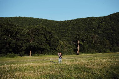 Kollarında bir çocuk tutan bir adam gülümseyip eğleniyor. Baba ve oğlu gün batımında papatya tarlasında. Genç aile parkta eğlenceli vakit geçirir..