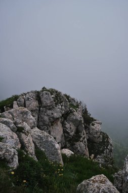 Yağmurdan önce yoğun kara sislerin arka planında dik kayalık bir dağ. Kafkasya 'daki Ulusal Park' ın doğası ve manzarası. Dağlarda soğuk bir yaz günü.