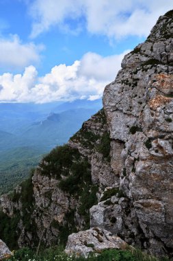 Dik kayalık dağ, ufuktaki kar kaplı dağların arka planına karşı. Kafkasya 'daki Ulusal Park' ın doğası ve manzarası. Dağlarda soğuk bir yaz günü.