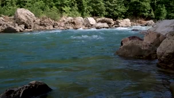 水平ズーム4Kスローモーションビデオ 大きな石の間で峡谷の青みがかった色合いの美しい嵐の山の川 背景に濃い緑の落葉樹林 — ストック動画