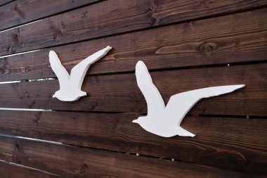 Birkaç kuş güneye uçuyor. Deniz kafesinin yaratıcı minimalist reklamları, martılarla pankart ve pankartlar. Tahta zemin üzerinde yapay martı figürlerinin siluetleri.
