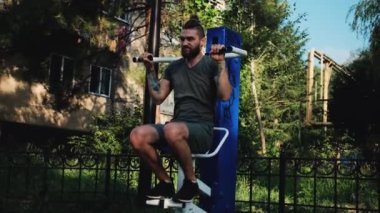 Forma gir ve sağlıklı bir yaşam sür. Ağırlığını iki elinle özel eğitim makinesine ver. Spor caddesi simülatöründe sakallı ve rastalı genç bir sporcunun güçlü eğitimi..