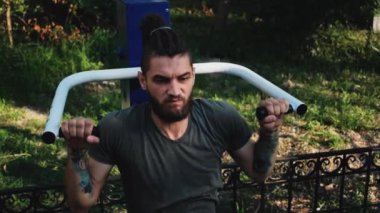 Forma gir ve sağlıklı bir yaşam sür. Ağırlığını iki elinle özel eğitim makinesine ver. Spor caddesi simülatöründe sakallı ve rastalı genç bir sporcunun güçlü eğitimi..