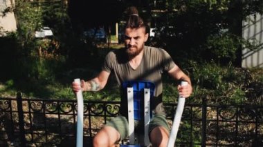 Forma gir ve sağlıklı bir yaşam sür. Ağırlığını iki elinle özel eğitim makinesine ver. Spor caddesi simülatöründe sakallı ve rastalı genç bir sporcunun güçlü eğitimi..