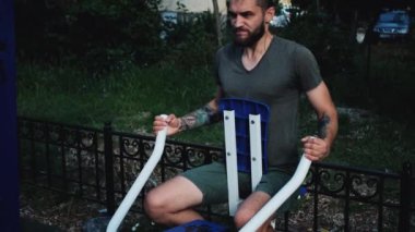 Forma gir ve sağlıklı bir yaşam sür. Ağırlığını iki elinle özel eğitim makinesine ver. Spor caddesi simülatöründe sakallı ve rastalı genç bir sporcunun güçlü eğitimi..