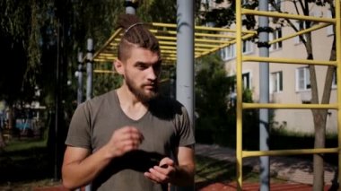 Sokakta dayanıklılık antrenmanına başlamadan önce, sporcu müzik dinlemeye karar verdi. Aktif yaşam tarzı kavramı. Sakallı ve rastalı beyaz bir adam kablosuz kulaklık takıyor..