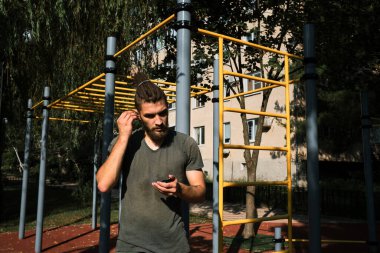 Aktif yaşam tarzı konsepti. Sakallı ve rasta saçlı beyaz bir adam dışarıda antrenman yapmadan önce kablosuz kulaklık takıyor. Spor hocası kulaklıkla müzik dinler..