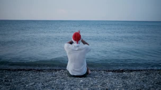 Hombre Joven Con Camisa Blanca Sombrero Rojo Santa Está Sentado — Vídeos de Stock