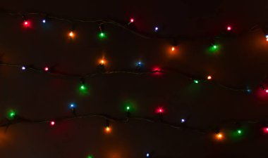 Siyah arka planda parıldayan renkli Noel ışıkları