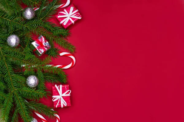 Disposición decoraciones de Navidad o flatlay con ramas de abeto, regalos, bolas y bastones de caramelo sobre fondo rojo con espacio de copia. — Foto de Stock