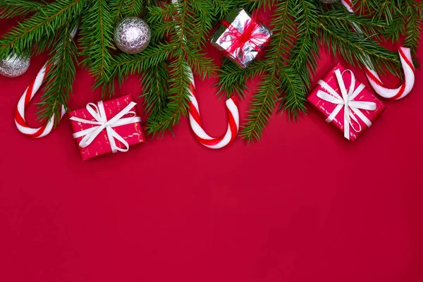 Árbol de Navidad composición borde diseño. Decoraciones rojas de Navidad, ramas de abeto sobre fondo rojo con espacio para copiar. — Foto de Stock