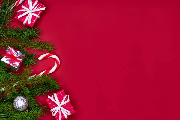 Karácsonyfa kompozíció határtervezés. Karácsonyi piros dekorációk, fenyő ágak piros háttér másolási hely. Stock Fotó