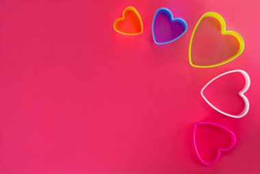 Pembe arka planda çok renkli kalp şeklinde kurabiye kesiciler..