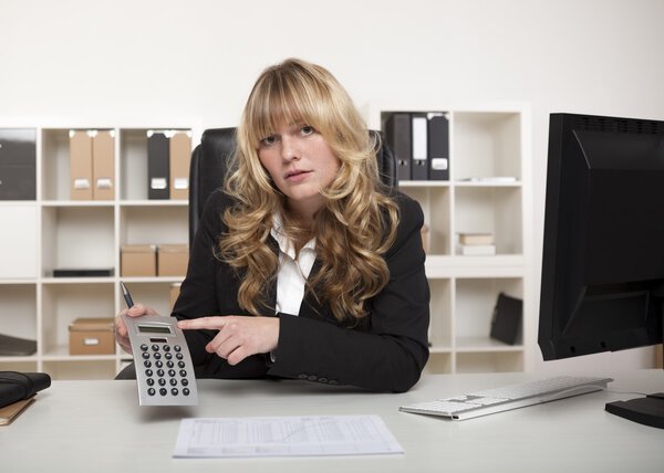 Бизнесвумен указывает на калькулятор
