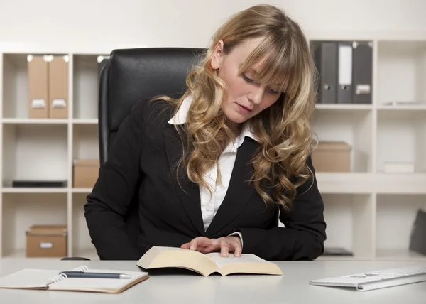 Junge Geschäftsfrau liest bei der Arbeit ein Buch — Stockfoto