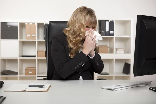 Businesswoman blowing her nose at her desk — Stock Photo, Image