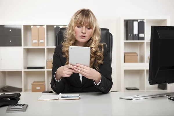 Jeune femme lisant une tablette au bureau — Photo