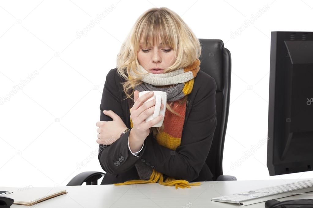 Cold businesswoman drinking a mug of hot coffee