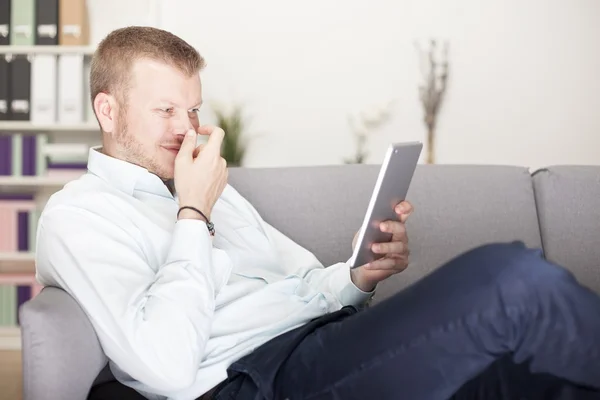 Homme ricanant à lui-même comme il lit sa tablette — Photo