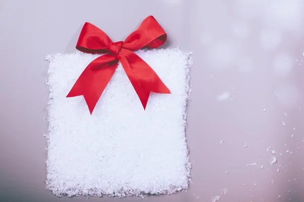 Christmas gift box in snow with red ribbon — Stock Photo, Image